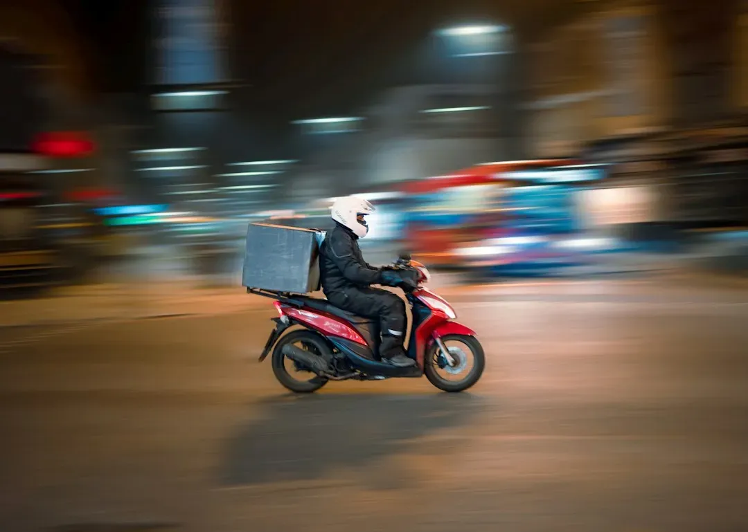 Repartidor en moto con un pedido a domicilio de noche