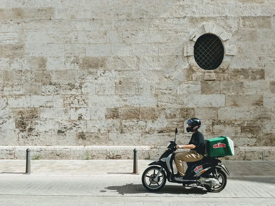 Repartidor en moto llevando un pedido por una calle de Valencia